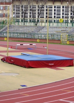 pole vault pit sitting in the middle of a track in front of a stadium