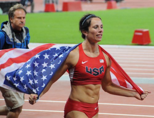 woman pole vaulter Jenn Suhr with American flag on her shoulders