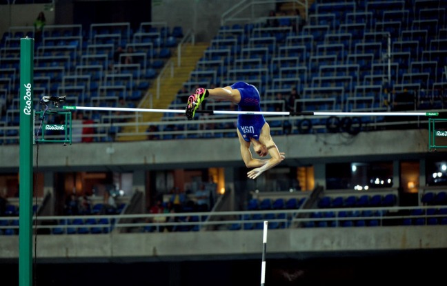 Sam Kendricks in blue USA uniform vaults over a bar in Rio in 2016 Olympics